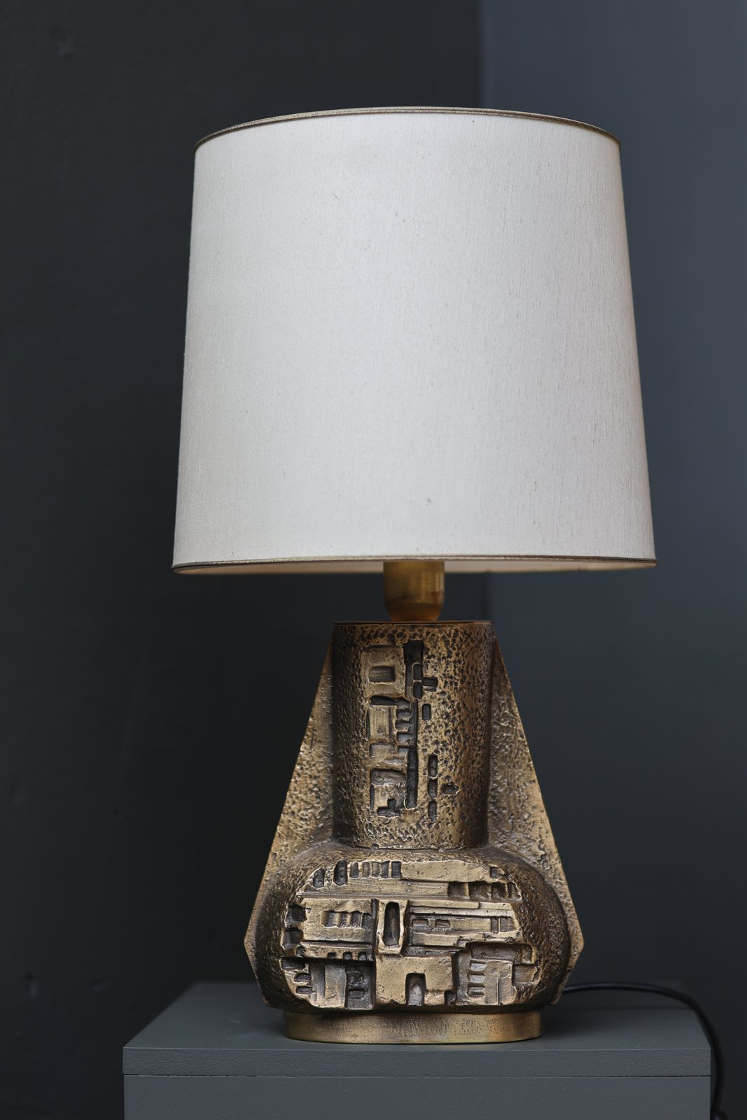 Brutalist bronze table lamp, 1970s Italy, geometric cast-relief base with cream linen shade