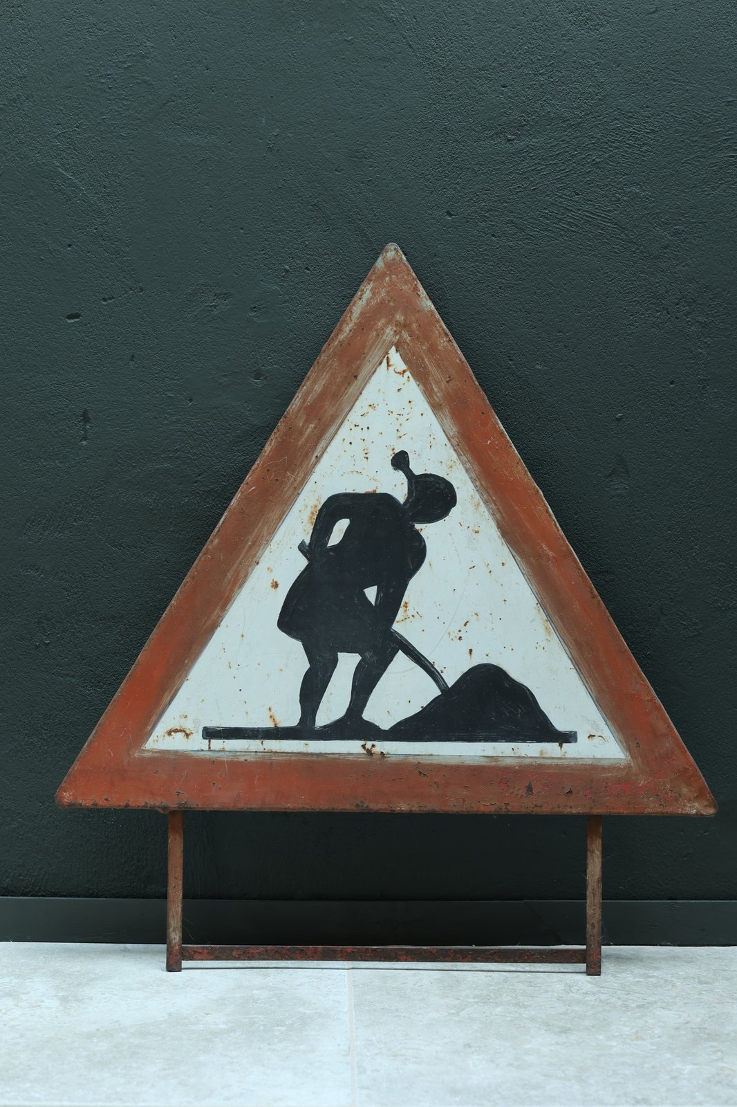Vintage Italian Panseri road sign, 1982, hand-painted black digging figure on a weathered orange triangle, on metal stand